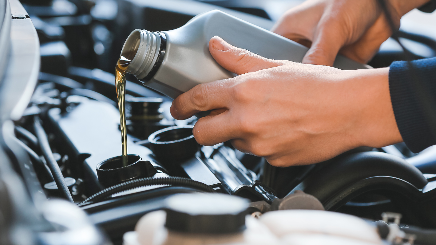 A person pouring oil into a car engine